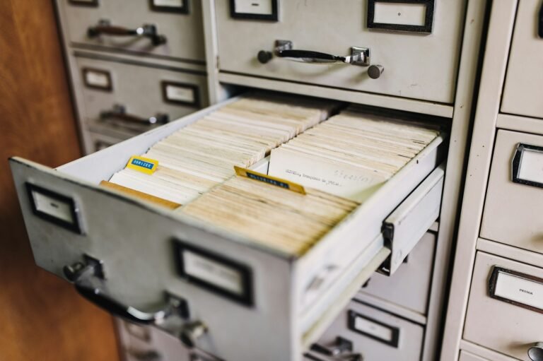 An open metal filing drawer containing neatly arranged paper index cards