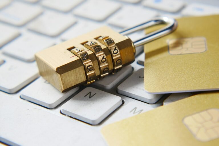 A brass combination padlock and payment cards resting on a white computer keyboard