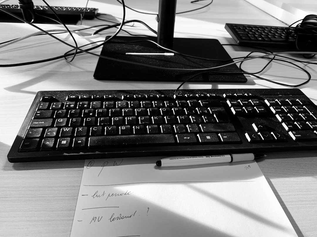 Black keyboard and monitor on a desk with handwritten notes
