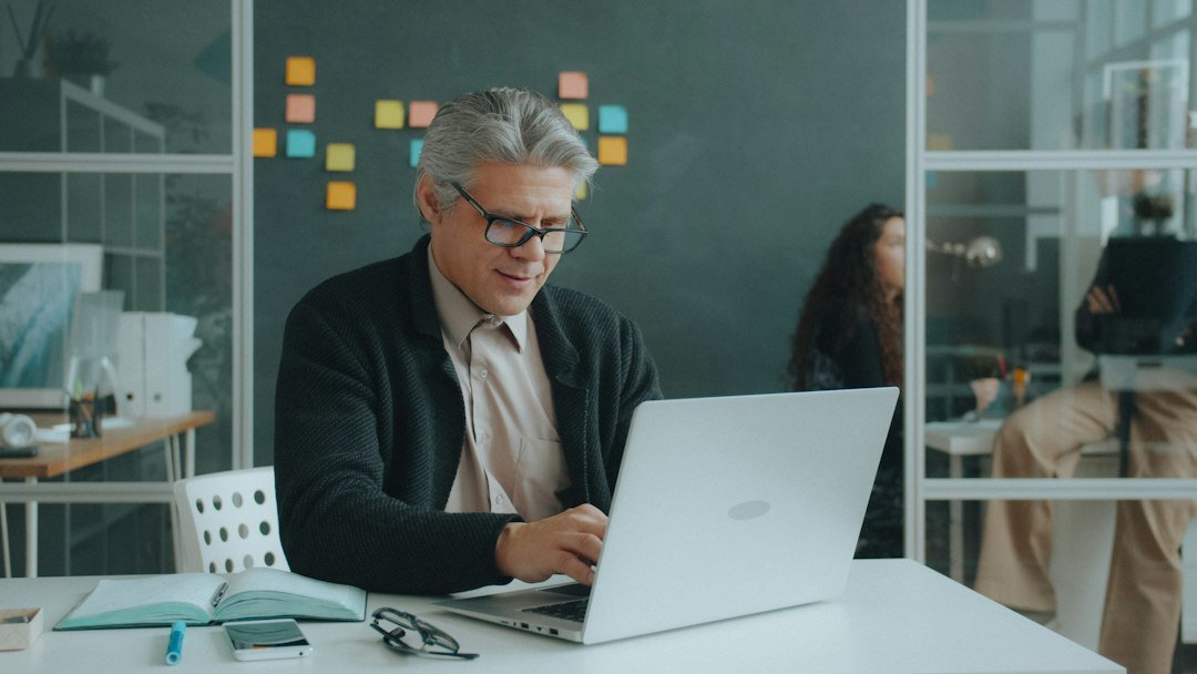 Man using a laptop at a table in an office