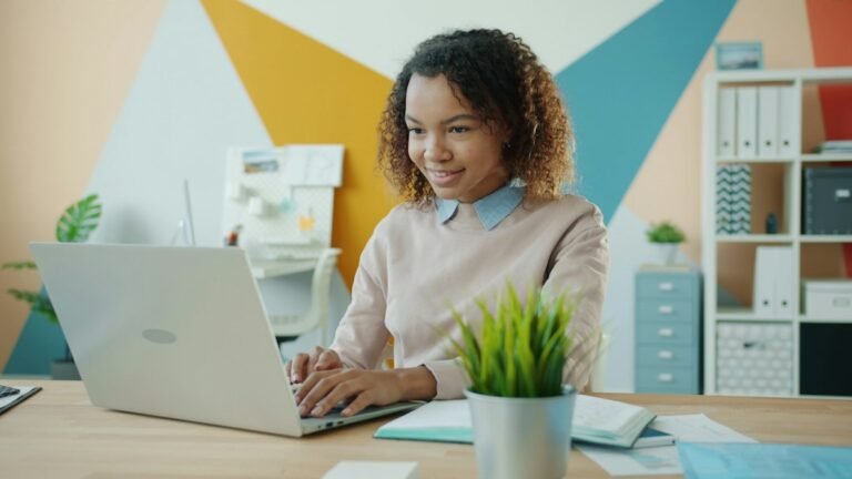 Woman typing on a laptop at a desk in a bright office